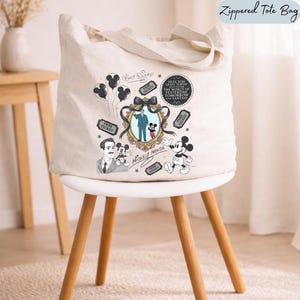 May include: A cream-colored zippered tote bag featuring a graphic print of Walt Disney and Mickey Mouse inside an ornate gold frame with a black bow. The design includes park tickets, balloons, and the text Here you leave today and enter the world of yesterday, tomorrow and fantasy.