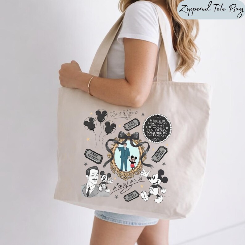 May include: A beige canvas tote bag featuring a black and white graphic print of Walt Disney, Mickey Mouse, balloons, park tickets, and a decorative frame. The text reads: Here you leave today and enter the world of yesterday, tomorrow and fantasy.