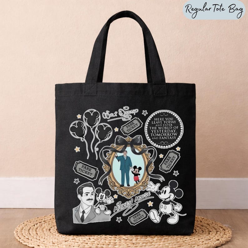 May include: A black tote bag featuring a white graphic print of Walt Disney, Mickey Mouse, balloons, park tickets, and a circular quote that reads: Here you leave today and enter the world of yesterday, tomorrow and fantasy. The design includes a central ornate gold-toned frame containing an illustration of Walt Disney holding Mickey Mouse's hand.