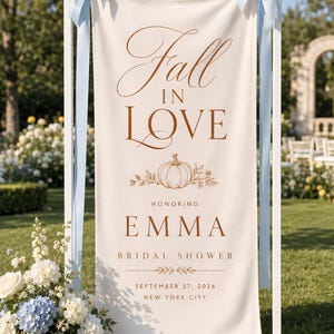 Puede incluir: Una pancarta de tela color crema suspendida de un marco de madera blanca con cintas de satén azul claro. La pancarta presenta texto marrón que dice Fall IN LOVE, HONORING EMMA BRIDAL SHOWER, SEPTEMBER 27, 2026, NEW YORK CITY y un gráfico de calabaza.