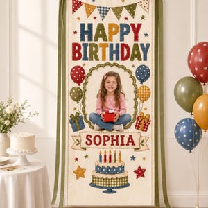 May include: A vertical fabric birthday banner featuring the text HAPPY BIRTHDAY and SOPHIA, decorated with colourful bunting, balloons, gift boxes, and a cake illustration. A central oval frame displays a photograph of a child holding a gift.