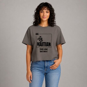 May include: A charcoal gray short-sleeved t-shirt featuring a black graphic print. The design includes quotation marks, a palm tree icon, the text "i'm so HAITIAN" inside a square frame, and the text "Enter your text here !" below the frame.