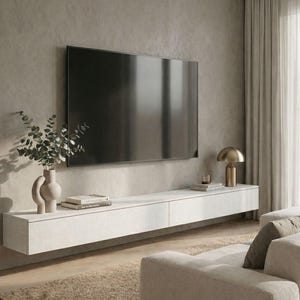 Puede incluir: Salón moderno con un televisor de pantalla plana grande en una pared gris. Debajo, un mueble flotante blanco con un jarrón con vegetación, libros y una lámpara dorada. Un sofá y una alfombra beige completan el diseño minimalista.