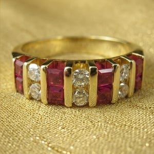 Könnte beinhalten: Ein Goldring mit einer abwechselnden Kanalfassung aus quadratisch geschliffenen roten Rubinen und rund geschliffenen klaren Diamanten. Das Design zeigt ein sich wiederholendes Muster aus zwei Rubinen und zwei Diamanten in einem Goldrahmen.