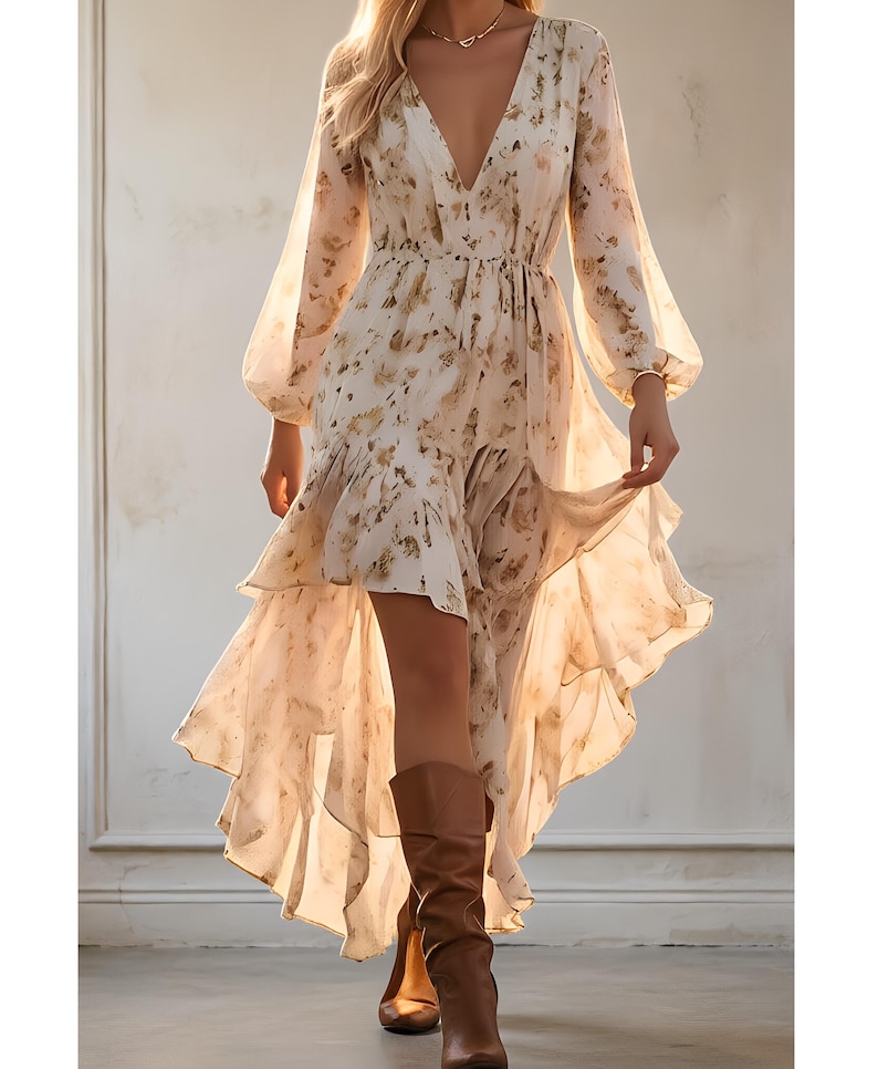 May include: A flowing, cream-colored dress with a floral pattern and a high-low hemline. The dress features long, sheer sleeves and a deep V-neck. Brown leather boots complete the look, creating a bohemian style.