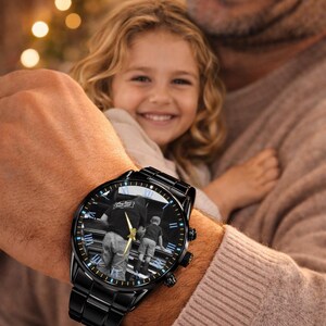 May include: Black wristwatch with a photo of a person and child on the watch face. The watch has a black band and a black face with gold hands. The text "Gift for Family" is at the top.
