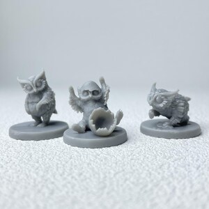 Puede incluir: Tres figuras de b&uacute;hos grises. Un b&uacute;ho est&aacute; de pie, otro est&aacute; saliendo de un huevo y el tercero parece estar en pleno vuelo. Cada figura est&aacute; sobre una base circular, adecuada para juegos de mesa o exhibici&oacute;n.