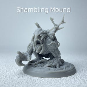 May include: A grey, 3D-printed miniature of a Shambling Mound monster. The creature has a gaping maw with sharp teeth, clawed hands, and a textured, plant-like appearance. The text "Shambling Mound" is above the figure.
