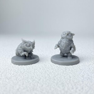 Puede incluir: Dos figuras de b&uacute;ho grises. Un b&uacute;ho est&aacute; agachado, el otro est&aacute; de pie. Ambos est&aacute;n sobre bases circulares. Las figuras tienen texturas de plumas detalladas y ojos grandes, lo que les da una apariencia caprichosa. Probablemente sean miniaturas para juegos de mesa o art&iacute;culos decorativos.