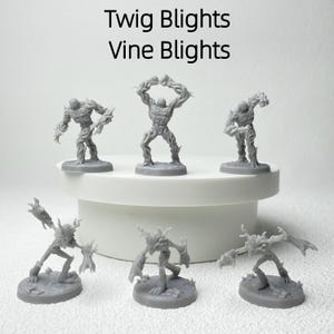 May include: A collection of gray miniature figures, resembling humanoid tree creatures, are displayed on a white platform. The figures vary in pose and design, with the text "Twig Blights Vine Blights" at the top. These figures are likely for tabletop gaming or collecting.