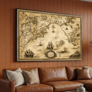 Puede incluir: Una impresión enmarcada de un mapa antiguo que representa una carta náutica detallada con veleros. El mapa está en tonos sepia, enmarcado en negro, y cuelga sobre un sofá de cuero marrón con cojines decorativos. El mapa muestra masas terrestres, rutas marítimas y barcos.