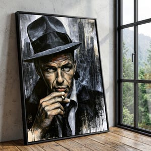 May include: A framed wall art print featuring a portrait of a man wearing a dark fedora hat and a coat, holding a lit cigarette. The artwork uses a monochromatic color palette with black, white, and grey tones, depicting a city skyline background.