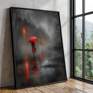 May include: Framed art print depicting a person with a red umbrella and coat walking in the rain. The artwork is primarily black, white, and gray, with pops of red from the umbrella and reflections in the wet pavement. The scene evokes a sense of solitude.