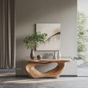 May include: A white ceramic mug with a black handle and the text "But First, Coffee" in a bold, black font. The mug is set against a blurred background, highlighting its simple design.