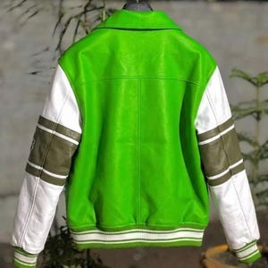 May include: A bright lime green varsity jacket featuring white sleeves with olive green horizontal stripes. The jacket includes a classic collar, a ribbed hem, and ribbed cuffs, all detailed with white and green striped patterns on the edges.