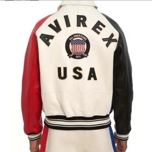 May include: A varsity jacket featuring a cream-colored back panel with the black text AVIREX and USA. A circular patch displays the text ALL AMERICANS ESTABLISHED 1975 with a US flag. The jacket has a red right sleeve and a black left sleeve.