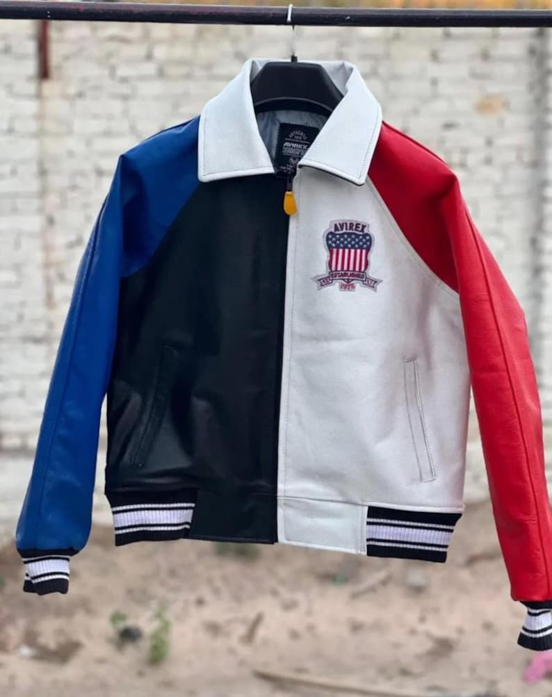 May include: A color-blocked jacket featuring a white collar, a blue left sleeve, a black front panel, and a white right front panel with a red sleeve. The chest displays an Avirex patch with a flag design. It includes a zipper closure and striped cuffs.