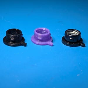May include: Three small, plastic components with a threaded interior and a circular base. One is black, one is purple, and the third is black with a silver interior. Each has a small, rounded tab extending from the base.