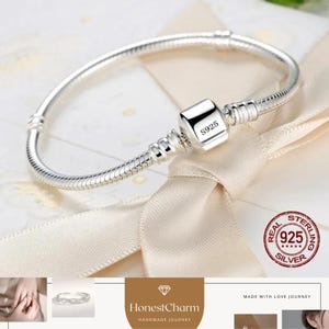 May include: A silver bracelet featuring a snake chain design and a square clasp, engraved with "S925". The bracelet is presented against a cream-coloured backdrop, with a "Real 925 Silver" stamp visible.