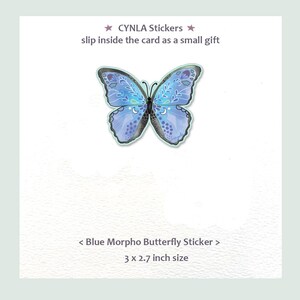 May include: A blue butterfly sticker with intricate white floral and crescent moon patterns on its wings. The text reads CYNLA Stickers, slip inside the card as a small gift, and Blue Morpho Butterfly Sticker, 3 x 2.7 inch size.