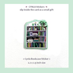 May include: A green sticker in the shape of a bookshelf, with various books, plants, and a sleeping cat. The sticker is 2.2 x 2.9 inches and includes the text "CYNLA Stickers" and "Happy Day."