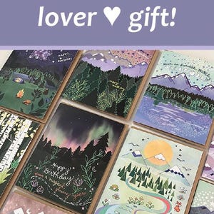 May include: A collection of illustrated greeting cards with mountain and forest scenes. The cards feature various designs, including mountains, trees, and the text "Happy Birthday". The phrase "best mountain lover gift!" is also visible.