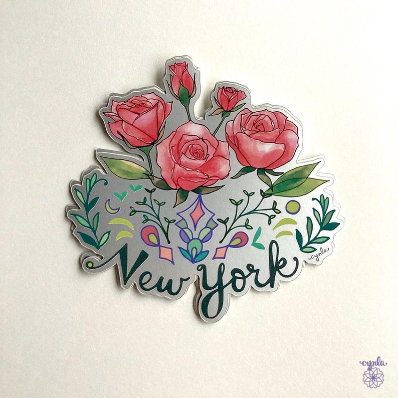 Puede incluir: Una pegatina plateada con un dise&ntilde;o floral con rosas rosas y hojas verdes. La pegatina dice "New York" en una fuente estilizada.