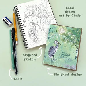 May include: An illustration of a heron in a serene setting, with the text "Have a peaceful birthday!" A sketch and tools are also visible. The words "hand drawn art by Cindy" are also in the image.