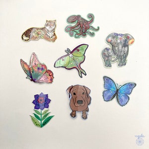 May include: A collection of eight die-cut stickers featuring a tiger, an octopus, a mother and baby elephant, two butterflies, a moth, a brown dog, and a purple flower. Each sticker displays detailed illustrations with vibrant colors and patterns.
