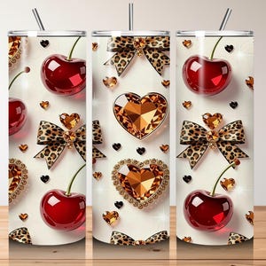 May include: Three stainless steel tumblers with a repeating pattern of cherries, leopard print bows, and jeweled hearts. Each tumbler has a silver straw and a white background. The design includes gold, red, and black accents.
