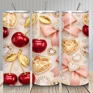 May include: Three stainless steel tumblers with a repeating pattern of cherries, gold leaves, diamond-encrusted hearts, and pink bows. Each tumbler has a silver straw and a cream-colored background. The tumblers are on a wooden surface.