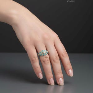 Close-up of a turquoise enamel statement ring on a woman’s hand with gold tone detailing.