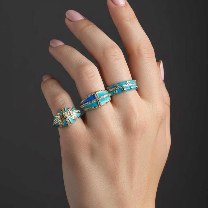 Turquoise enamel statement ring set worn on a woman’s hand, gold tone fashion jewelry for everyday style.