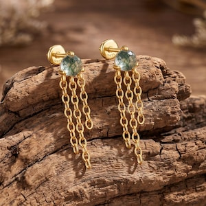May include: A pair of gold-tone stud earrings featuring a round, faceted green moss agate stone at the top. Each earring has three delicate gold-tone chains hanging from the base of the stone. The back of the earring post is clearly marked with 925.
