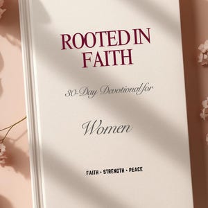 May include: A hardcover book titled "ROOTED IN FAITH" with the subtitle "30-Day Devotional for Women." The cover is off-white with burgundy text and the words "FAITH • STRENGTH • PEACE" at the bottom. The book is surrounded by pink flowers.