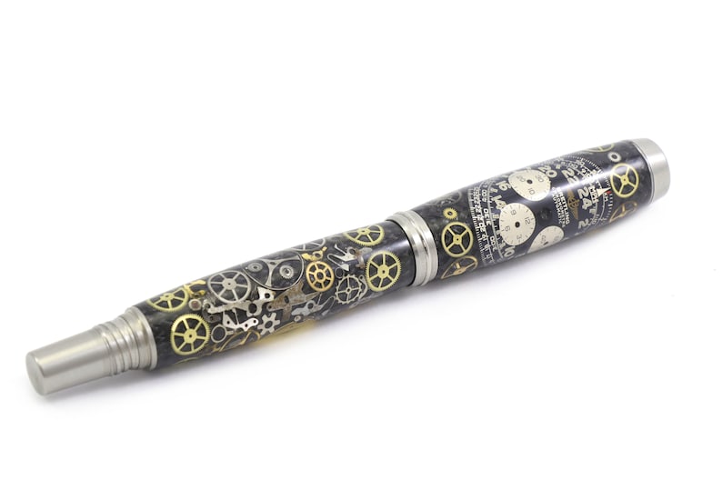 May include: A unique pen with a black and silver body, adorned with intricate clock gears in gold and silver. The pen features a silver tip and accents, showcasing a steampunk aesthetic. The design includes watch faces and detailed mechanical elements.