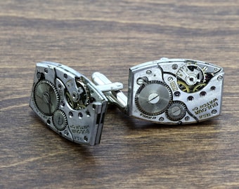 May include: A pair of silver cufflinks with exposed watch mechanisms. The cufflinks are engraved with "BULOVA WATCH CO. USA 17 JEWELS".