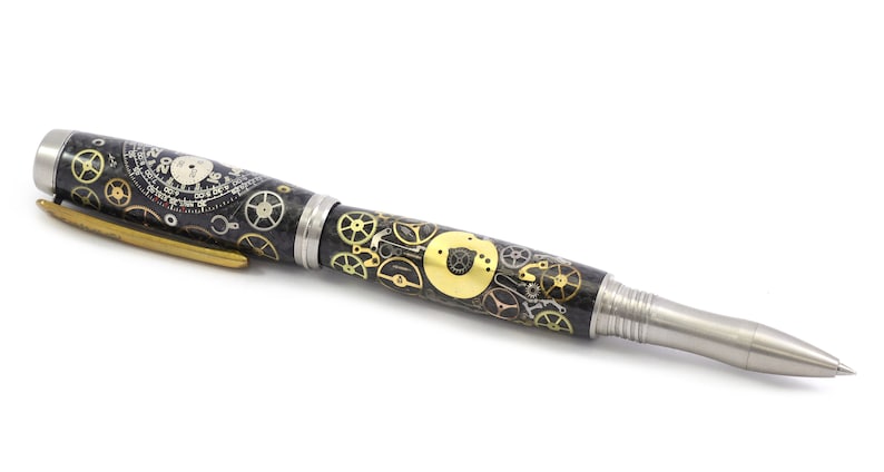 May include: A detailed pen with a steampunk design. The pen features a black barrel adorned with gold and silver gears, a silver tip, and a gold clip. The pen's design incorporates elements of watchmaking.