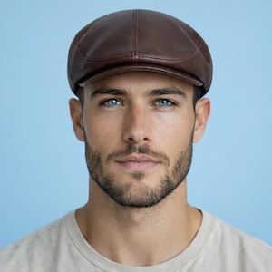 May include: A brown leather newsboy cap. The cap has a rounded crown and a short, stiff brim. The leather appears to be smooth and has a slight sheen. The cap is a classic style, suitable for various outfits.