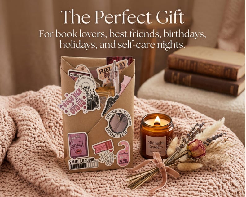 Op de afbeelding: Een bruin papieren cadeauzakje versierd met diverse stickers met boeken als thema, waaronder een lezend skelet, een 'Midnight Readers Book Club'-embleem en de tekst 'Smut Loading'. Daarnaast staat een amberkleurige glazen kaars en een droogboeket.