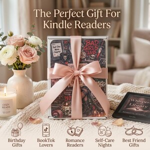 May include: A rectangular gift box wrapped in a pale pink satin ribbon, featuring a dark graphic print with text reading Bad Girls Club and Just One More Chapter. Beside it sits a white vase with pink roses, a candle labeled Cozy Reads, and a Kindle.