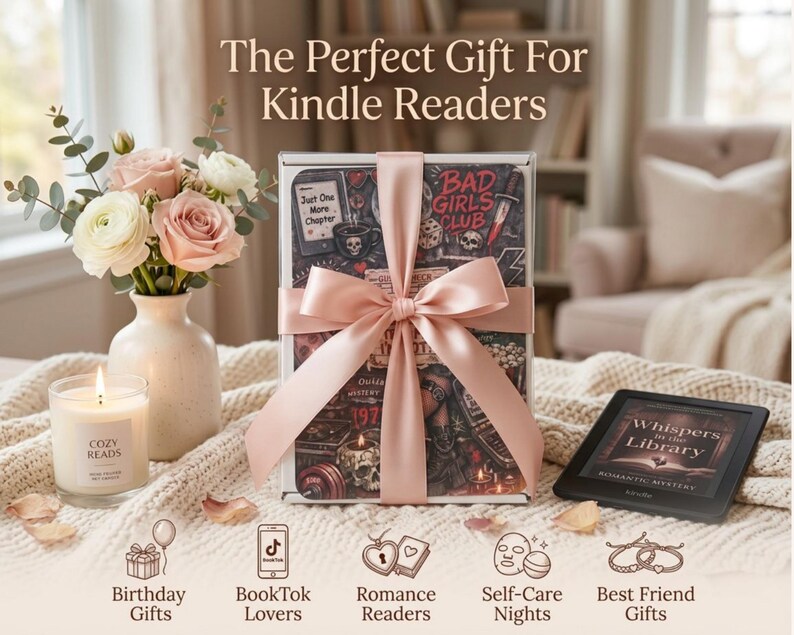 May include: A rectangular gift box wrapped in a pale pink satin ribbon, featuring a dark graphic print with text reading Bad Girls Club and Just One More Chapter. Beside it sits a white vase with pink roses, a candle labeled Cozy Reads, and a Kindle.