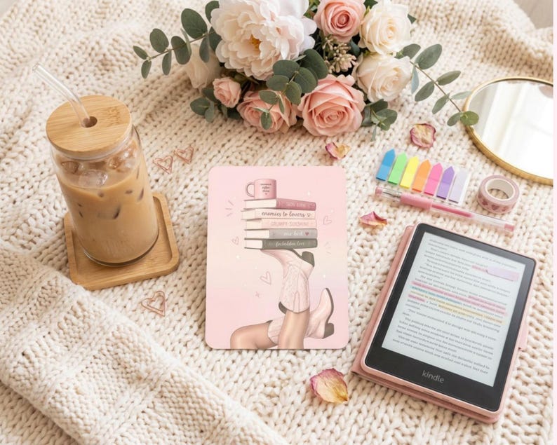 May include: A rectangular e-reader skin featuring a pink gradient background with an illustration of a stack of books balanced on a pair of light-colored cowboy boots. The design includes small heart accents and a coffee mug graphic on the top book.