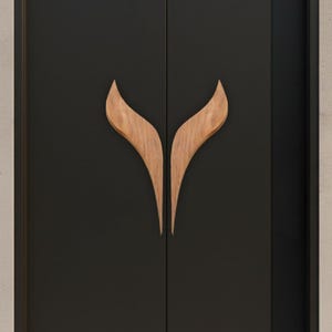 May include: A close-up of a black door with two wooden, leaf-shaped door handles. The handles are made of light-colored wood and are symmetrically placed on the door. The door appears to be part of a modern interior design.