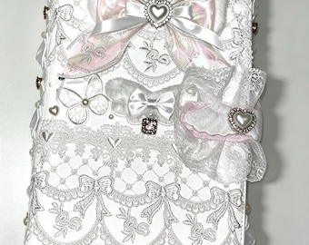 May include: White journal with detailed lace and bow decorations. Includes a large bow with a heart charm, smaller bows, and a butterfly accent. The journal is embellished with pearls and delicate features.