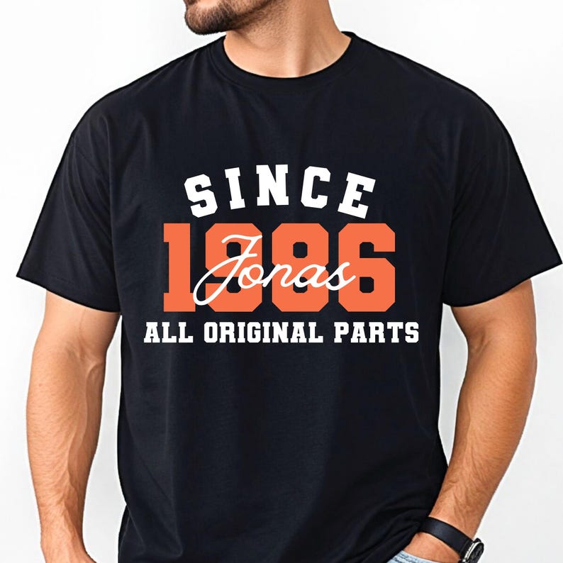 May include: Black t-shirt featuring the text "SINCE 1986 Jonas ALL ORIGINAL PARTS" in white and orange. The shirt has a crew neck and is likely made of cotton.