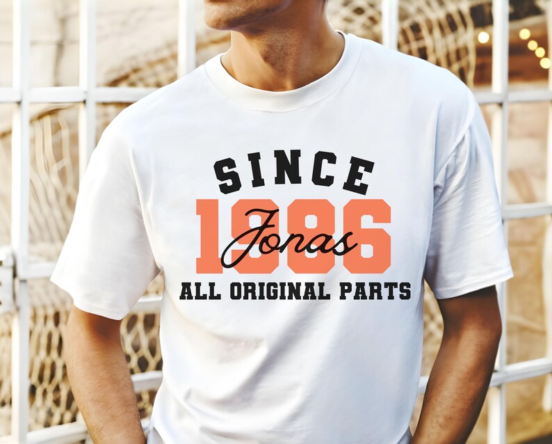 May include: White t-shirt with the text "SINCE 1986 Jonas ALL ORIGINAL PARTS" in black and coral lettering. The shirt has a crew neck and short sleeves.