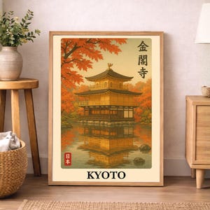 Peut inclure: Une affiche encadrée représentant un temple japonais doré se reflétant dans l'eau, entouré de feuillage d'automne. Le mot "KYOTO" est imprimé en bas. L'œuvre est exposée dans une pièce avec un sol en bois.