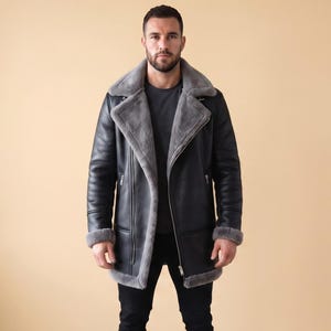May include: A black leather jacket with a wide, grey shearling-lined collar and cuffs. The jacket features a front zip closure, silver-toned hardware, and a long-line silhouette. It is worn over a dark grey t-shirt and black trousers.