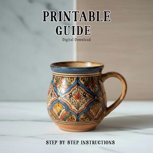 May include: A patterned ceramic mug with a brown handle and a blue rim. The mug has a detailed, colorful design. The text "PRINTABLE GUIDE" and "STEP BY STEP INSTRUCTIONS" are displayed above and below the mug.